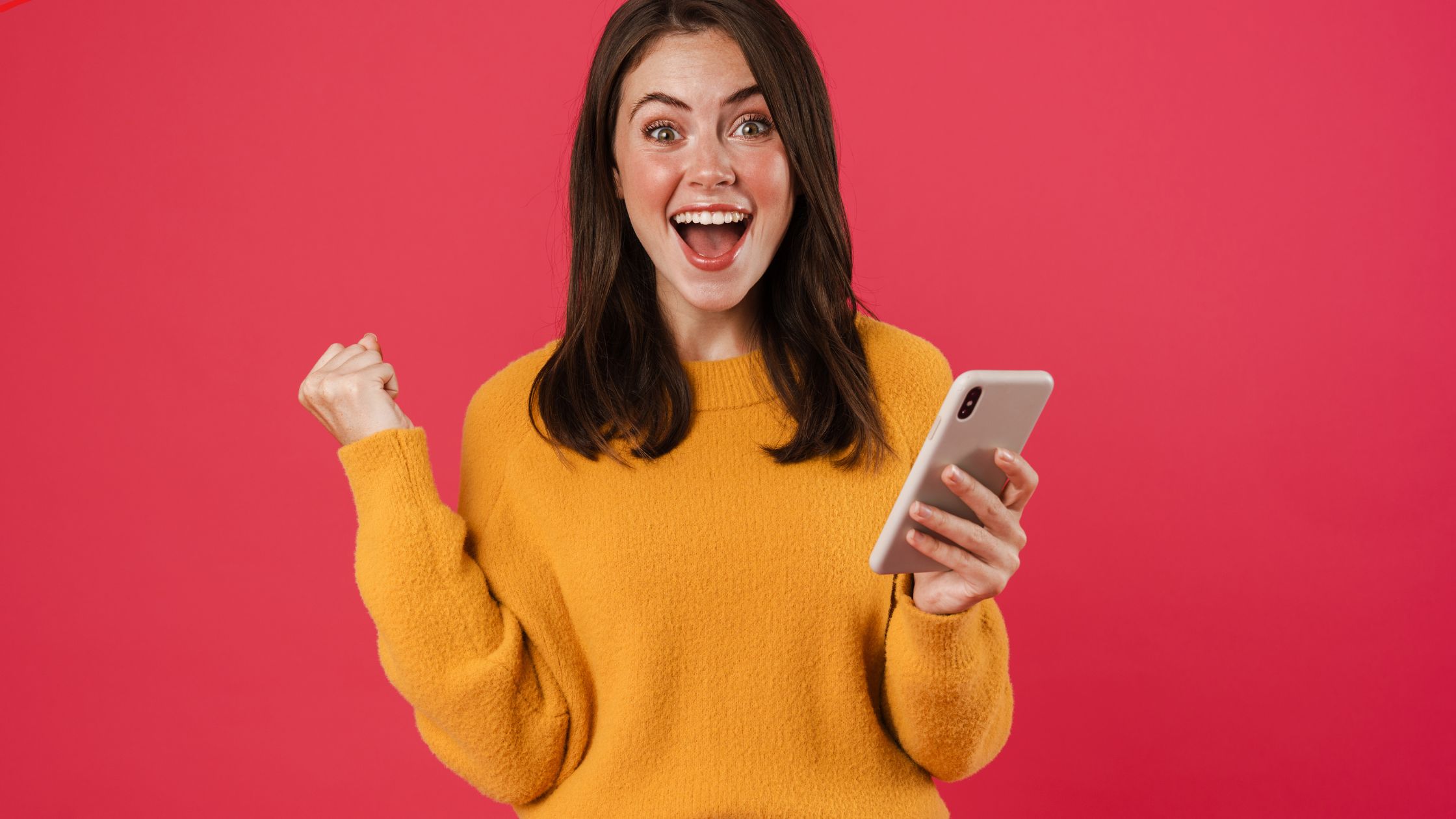 woman holding a phone looking excited with a red background