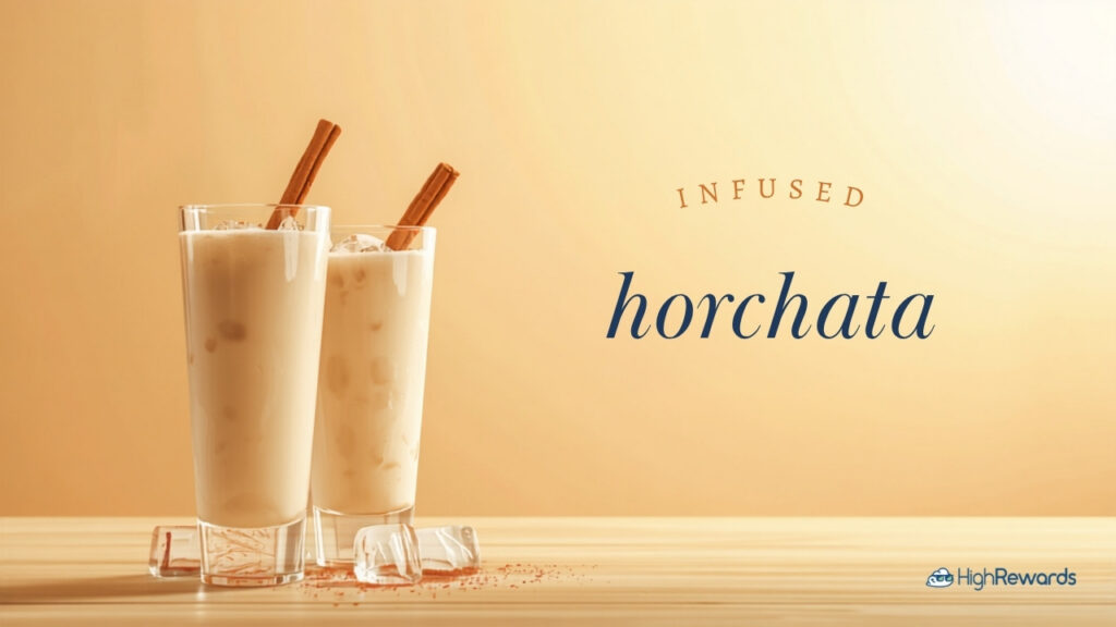 Two tall glasses of creamy infused horchata over ice with cinnamon sticks on a light wood surface